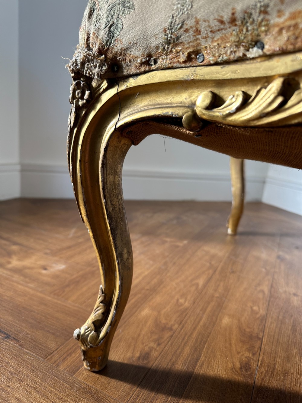A 19th-century French giltwood centre stool featuring carved Rococo scrollwork, cabriole legs, and floral upholstered seating. View IV