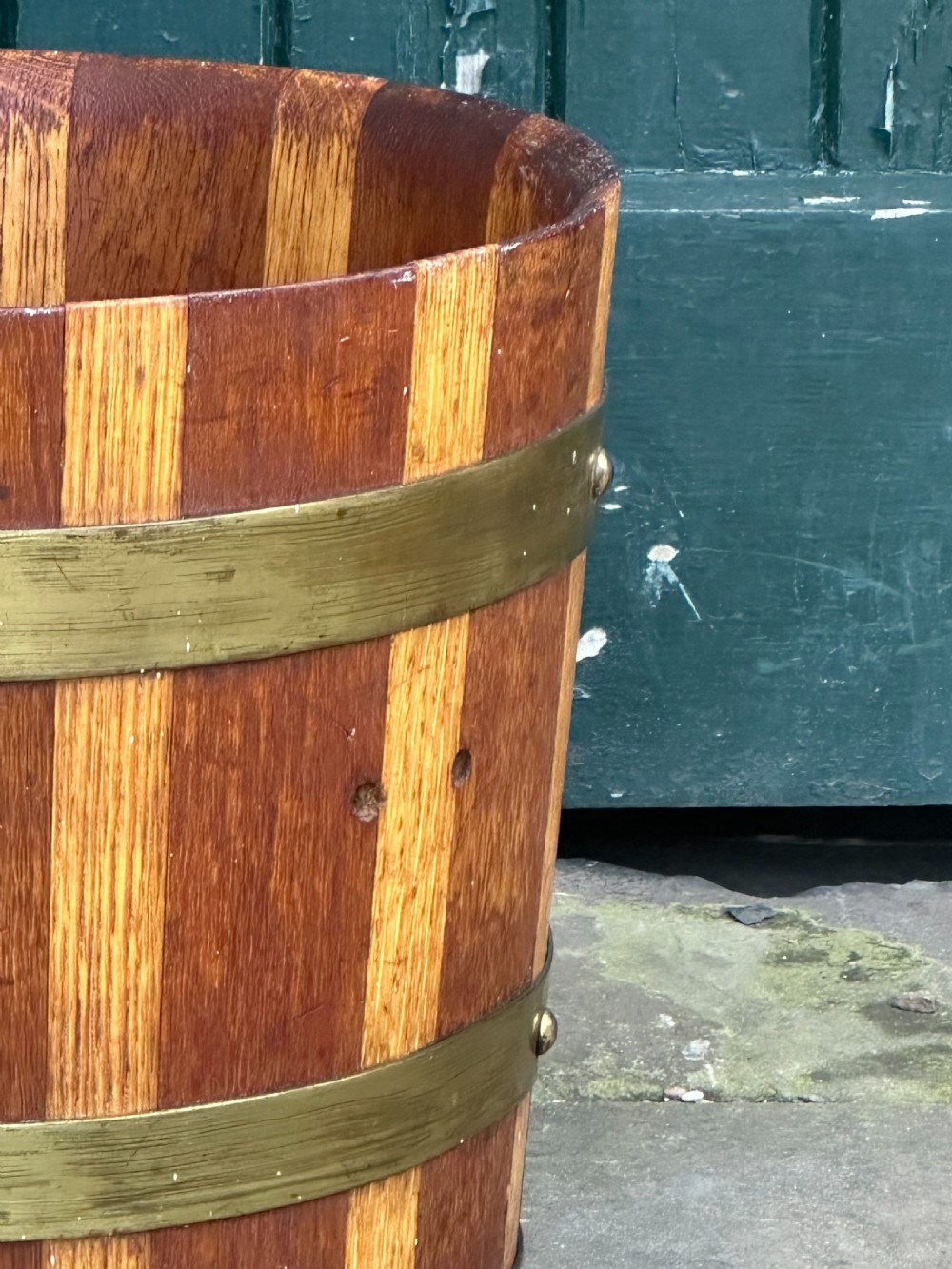 An antique Scottish coopered wooden peat bucket with alternating light and dark staves bound by three brass hoops. View II