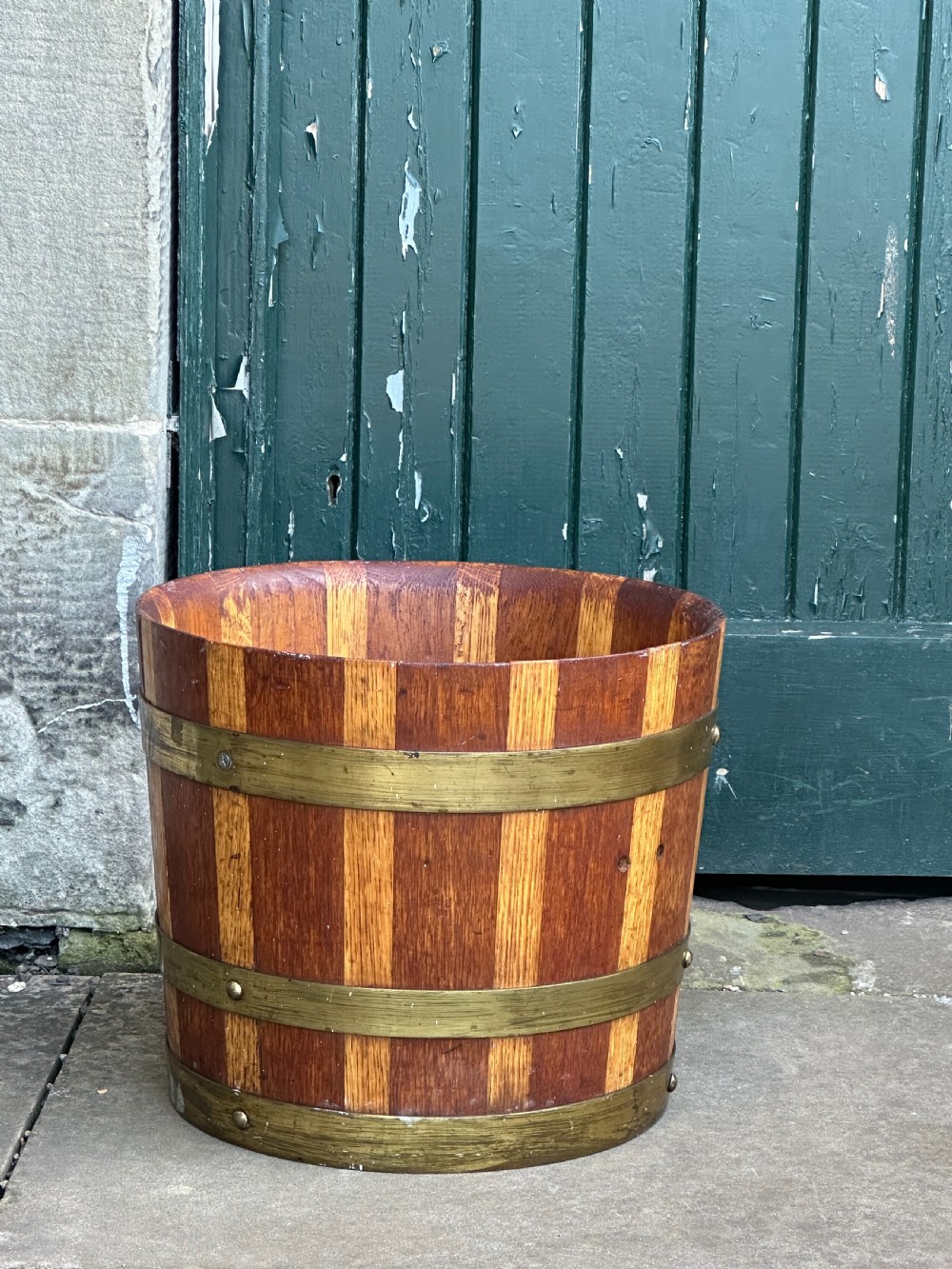 An antique Scottish coopered wooden peat bucket with alternating light and dark staves bound by three brass hoops. View III