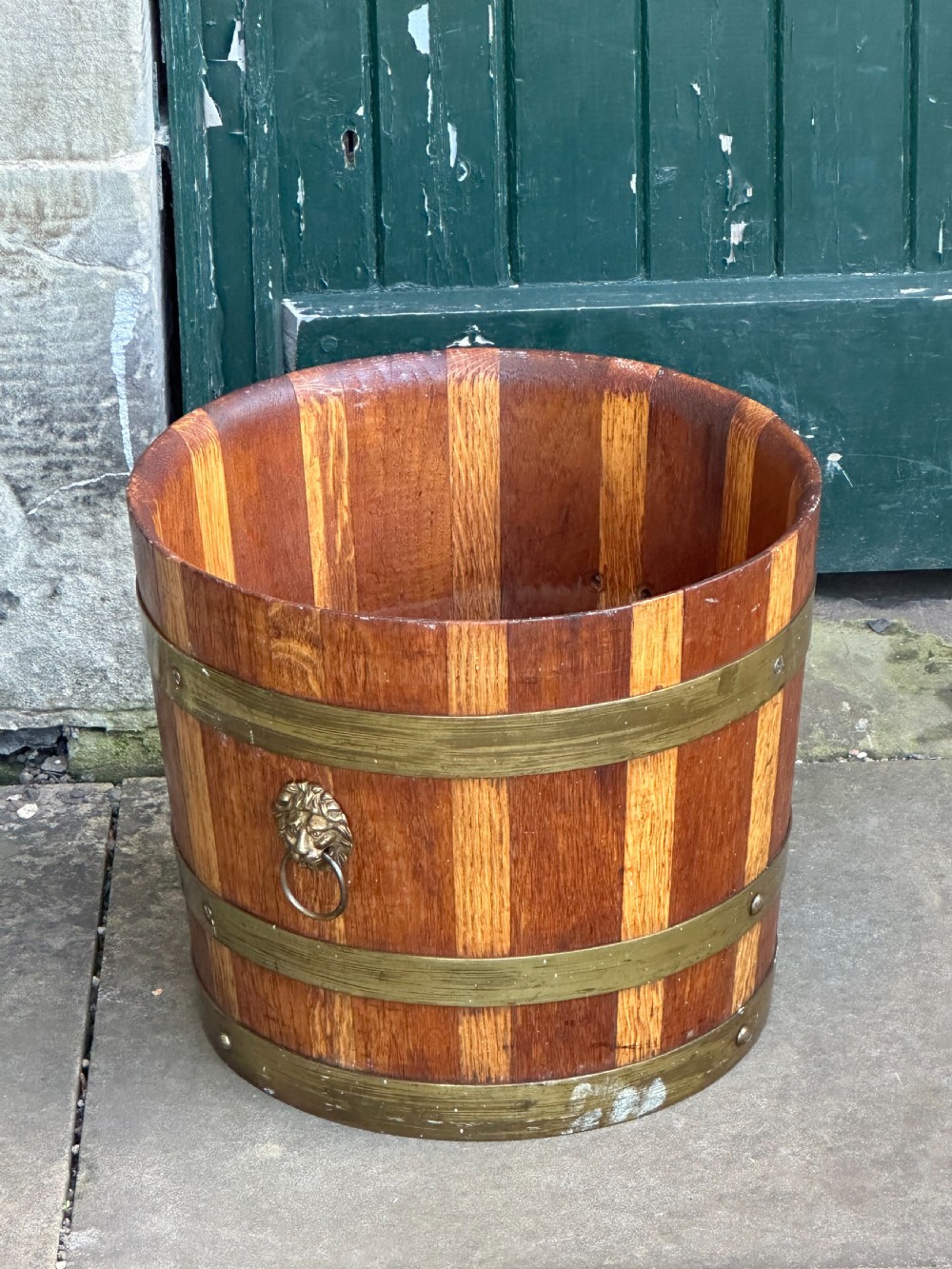 An antique Scottish coopered wooden peat bucket with alternating light and dark staves bound by three brass hoops. View IV