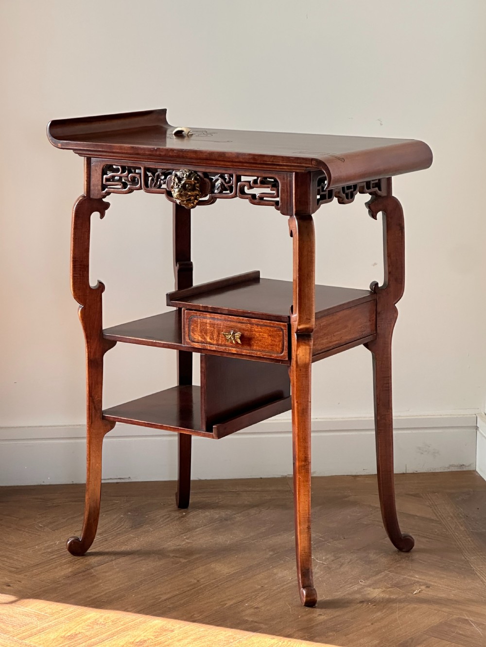 A late 19th-century French Japonisme side table featuring a curved pagoda top, open asymmetrical shelves, pierced wood carving, and a gilt-bronze motif.