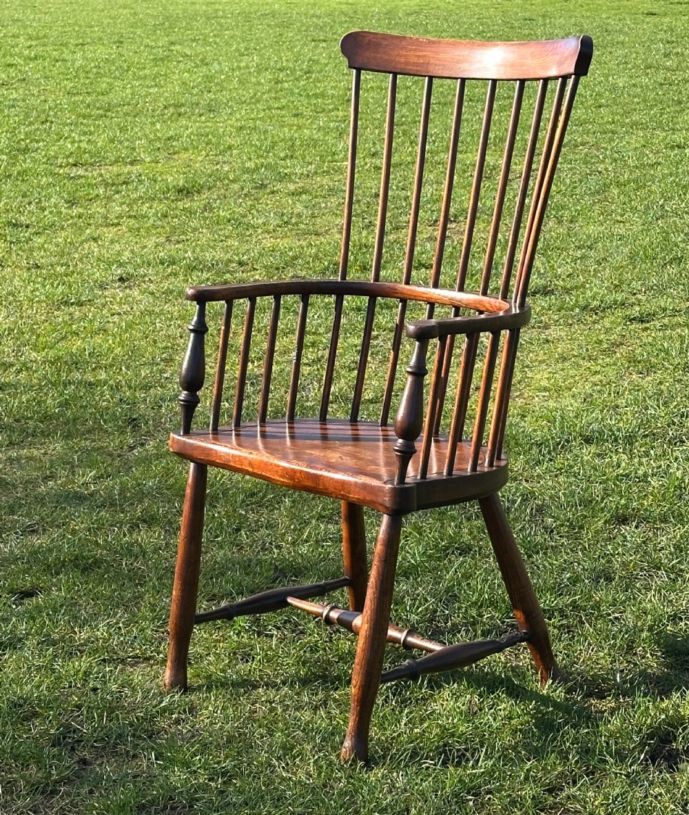 A Scottish Darvel Windsor armchair featuring a high spindle back, bentwood crest rail, curved armrests on turned supports, and a solid wood seat.