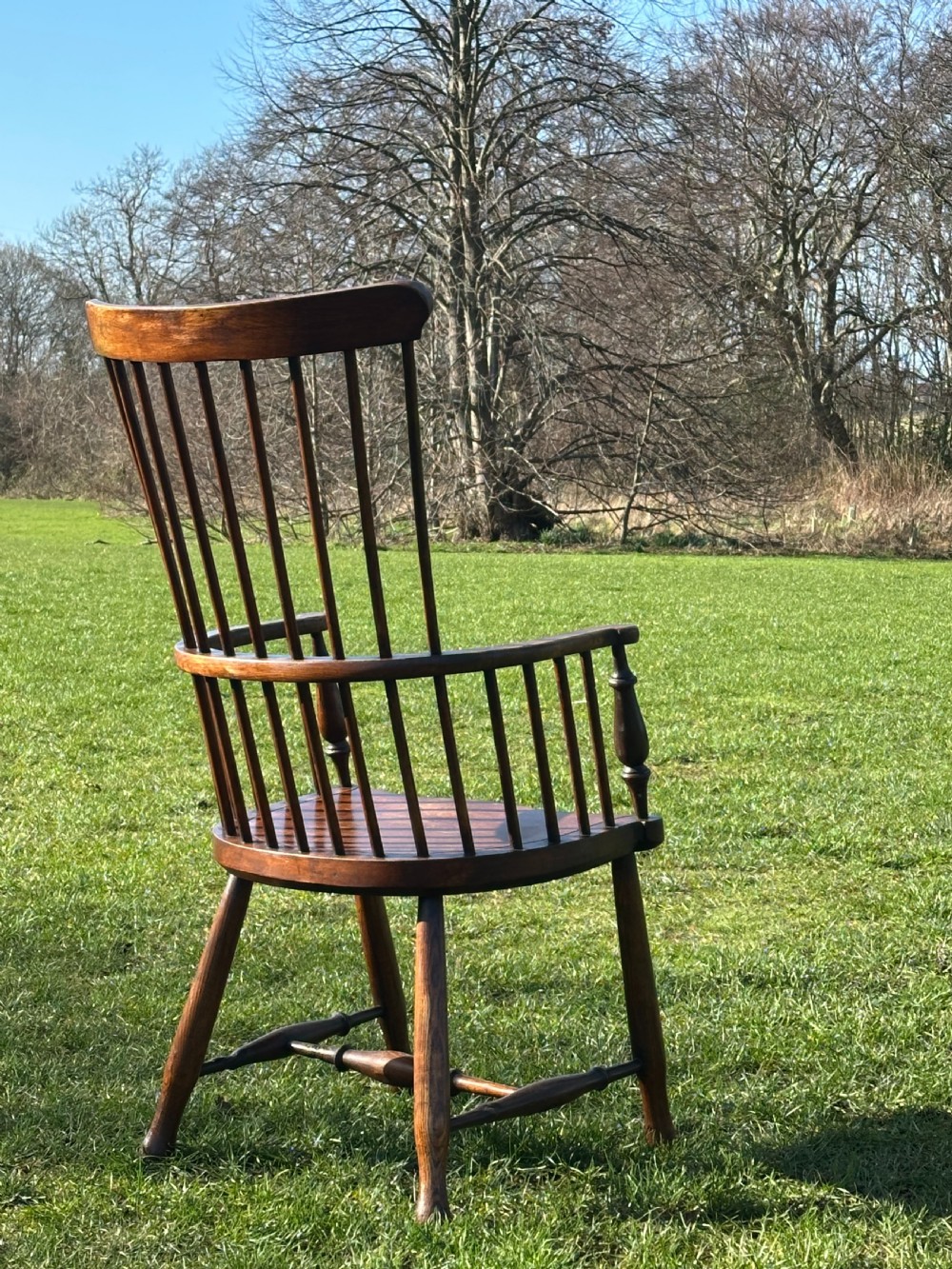 A Scottish Darvel Windsor armchair featuring a high spindle back, bentwood crest rail, curved armrests on turned supports, and a solid wood seat. View X