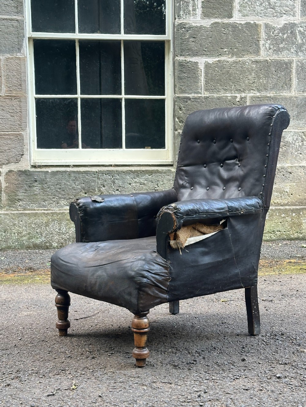 A Victorian library armchair upholstered in worn dark brown leather featuring a buttoned backrest, padded arms, and turned wooden front legs. View VI