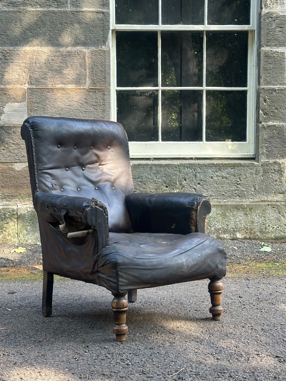 A Victorian library armchair upholstered in worn dark brown leather featuring a buttoned backrest, padded arms, and turned wooden front legs. View III