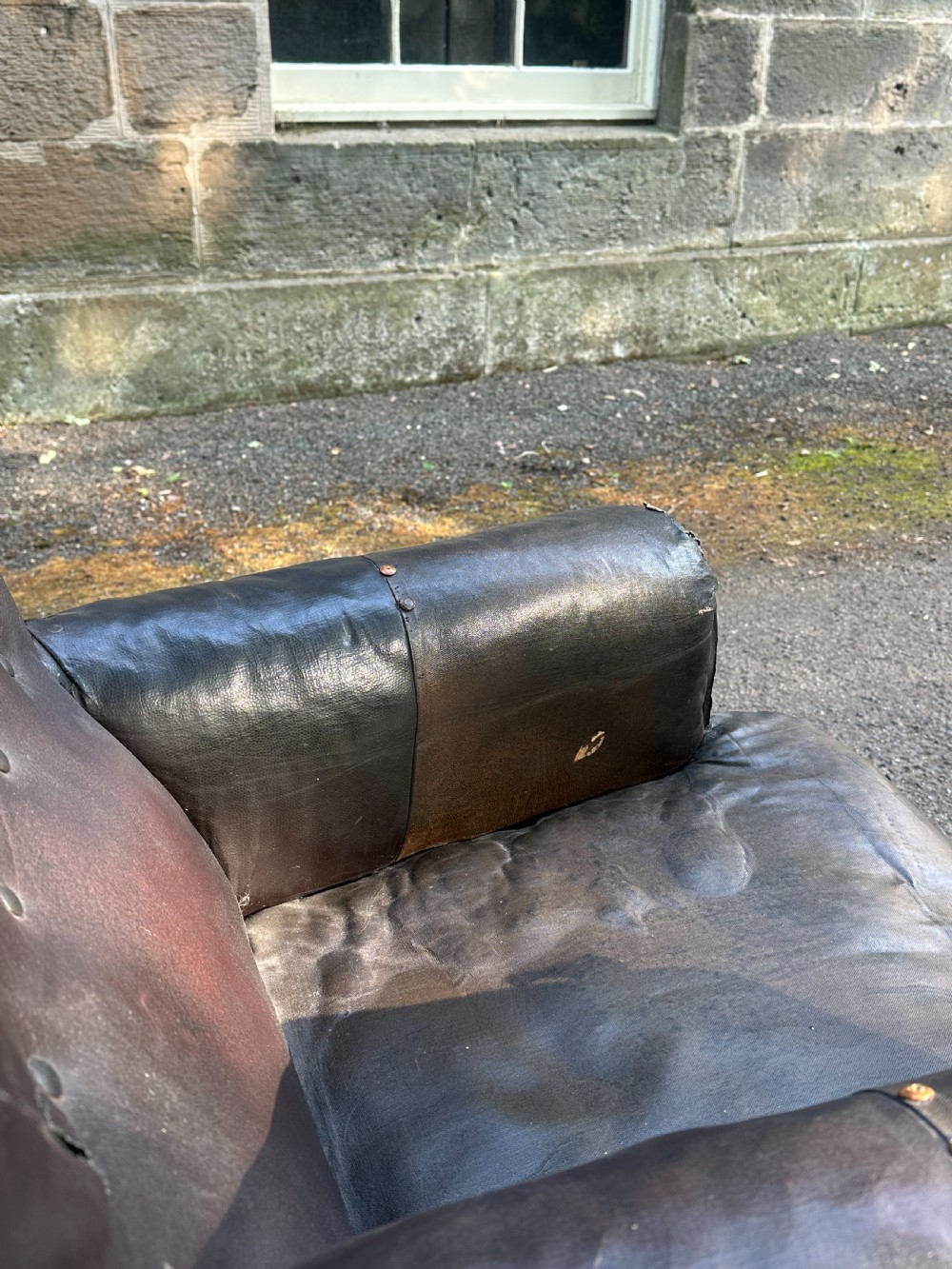 A Victorian library armchair upholstered in worn dark brown leather featuring a buttoned backrest, padded arms, and turned wooden front legs. View V