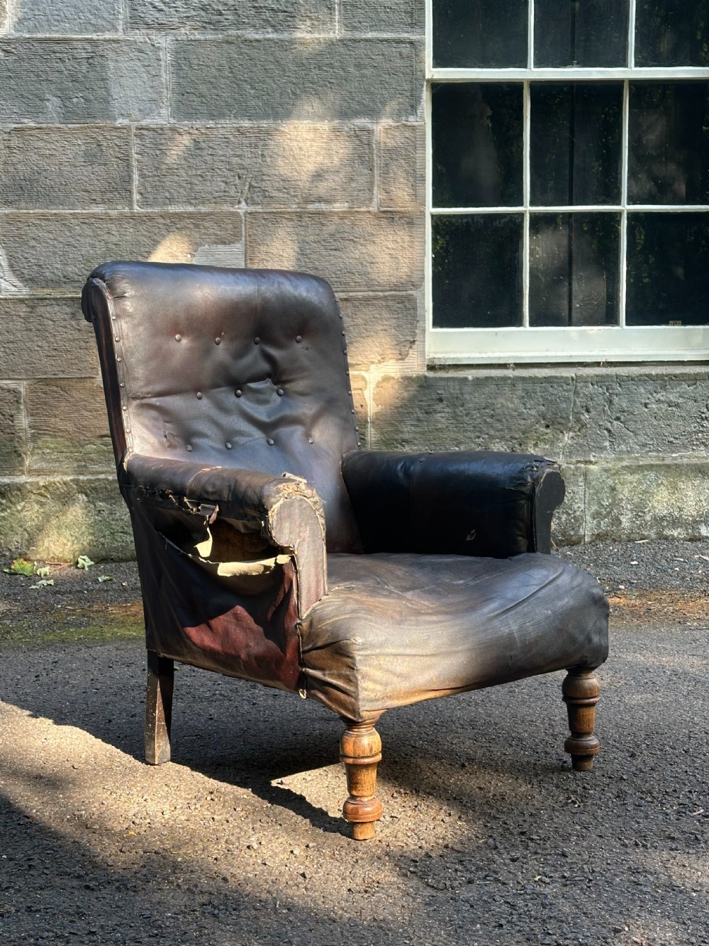 A Victorian library armchair upholstered in worn dark brown leather featuring a buttoned backrest, padded arms, and turned wooden front legs. View VII