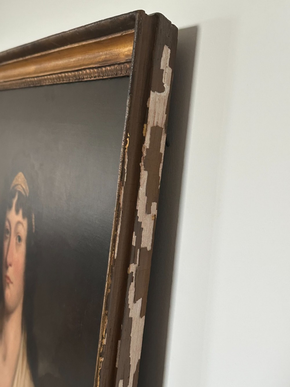 An early nineteenth-century portrait painting on canvas showing a woman in a cream Empire-line dress framed in carved gold leaf wood. View V