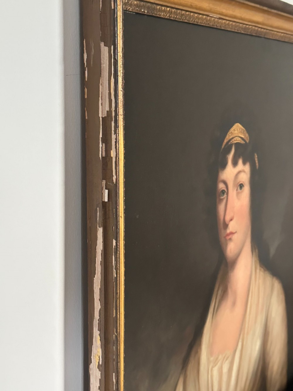 An early nineteenth-century portrait painting on canvas showing a woman in a cream Empire-line dress framed in carved gold leaf wood. View VI