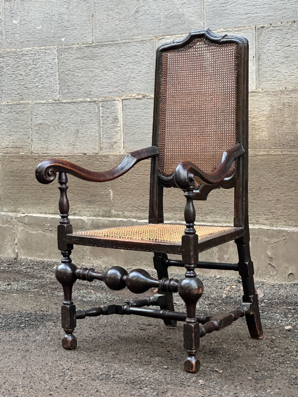 A dark painted walnut open armchair featuring a high woven cane back panel, scrolled arms, a cane seat, and bulbous turned stretchers. View III