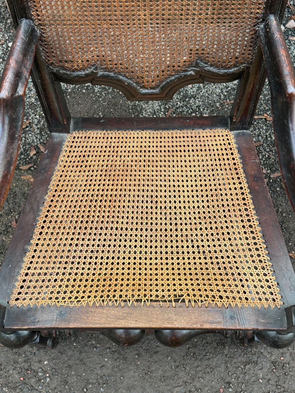 A dark painted walnut open armchair featuring a high woven cane back panel, scrolled arms, a cane seat, and bulbous turned stretchers. View V
