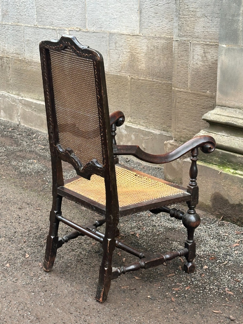A dark painted walnut open armchair featuring a high woven cane back panel, scrolled arms, a cane seat, and bulbous turned stretchers. View VII