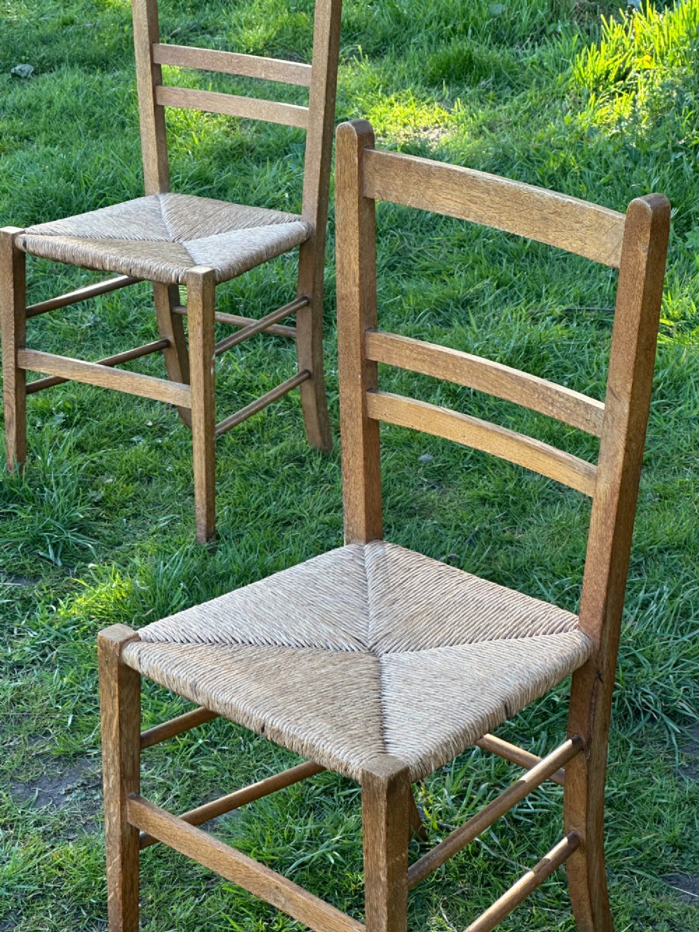 A pair of Arts and Crafts oak and rush seated chairs in the manner of Heals View III