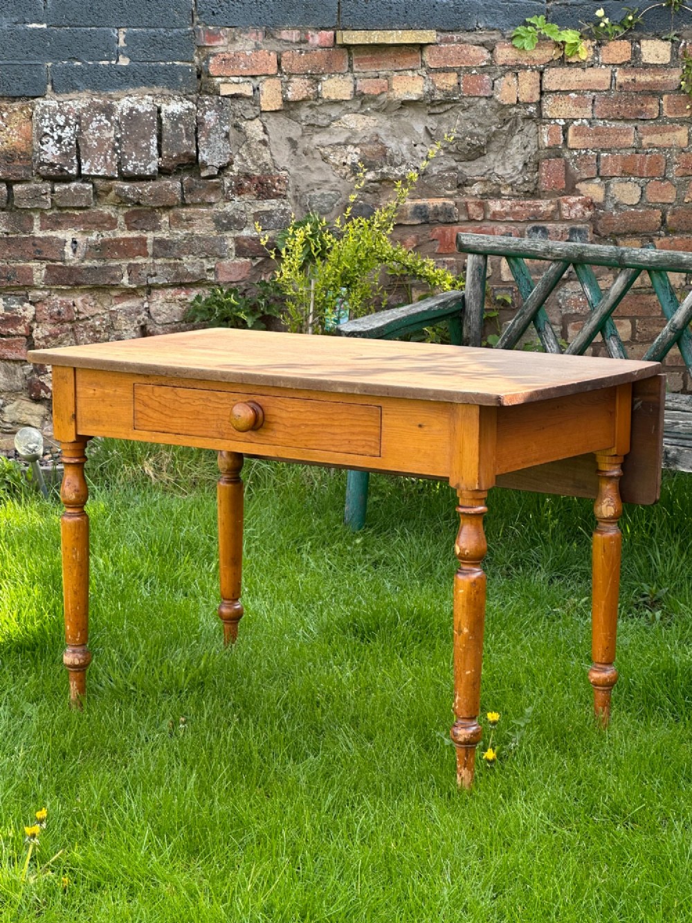 A 19th-century pine kitchen preparation table featuring turned legs, a single frieze drawer with a wooden knob, and a drop-leaf extension. View III