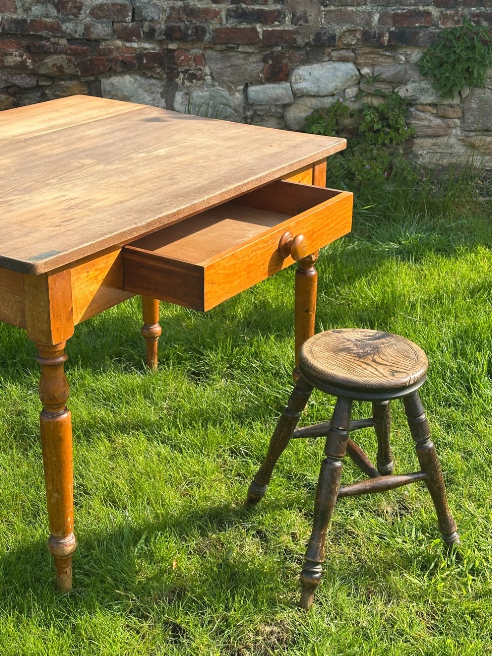 A 19th-century rustic wooden stool featuring a circular solid elm seat and four dark turned splayed legs with stretchers. View II