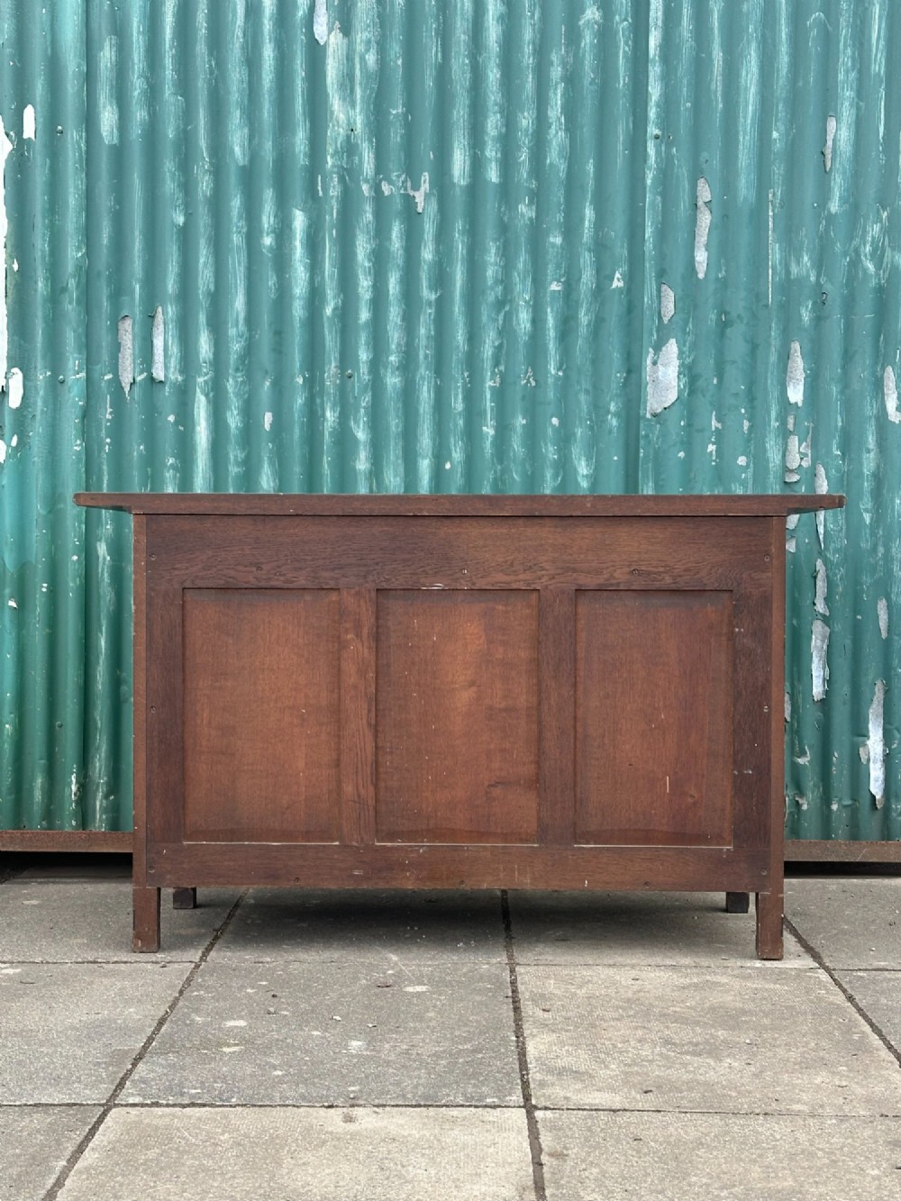 A dark oak Arts and Crafts side cabinet with two upper drawers, lattice glazed double doors, and decorative brass mounts. View IX