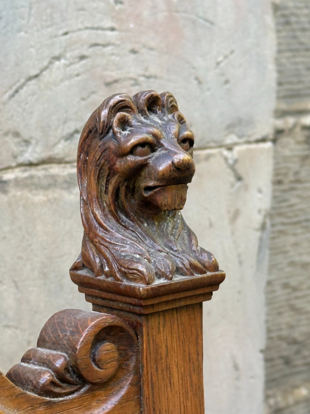 A carved oak hall chair featuring lion mask finials, shell cresting, turned front legs on castors, and sage green pattern upholstery. View III