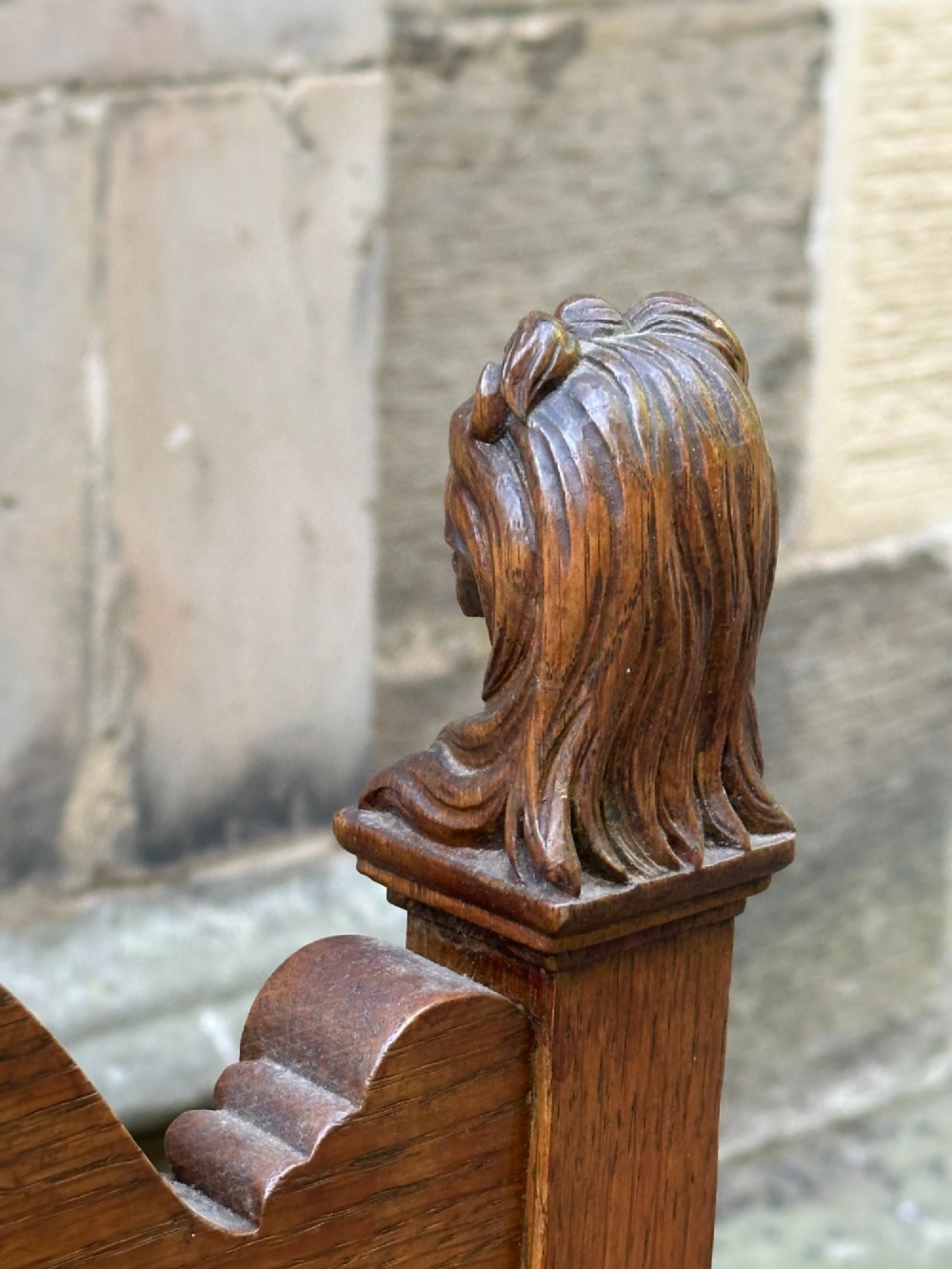 A carved oak hall chair featuring lion mask finials, shell cresting, turned front legs on castors, and sage green pattern upholstery. View IV