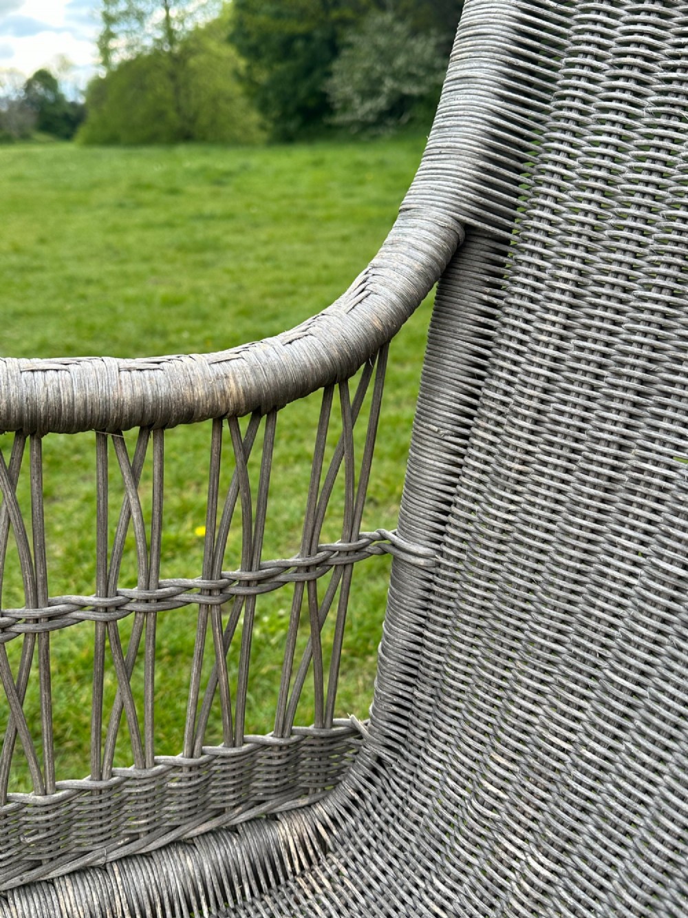 An early 20th-century handwoven cane armchair featuring a high backrest, openwork arms, and curved structural stretchers in weathered grey. View II
