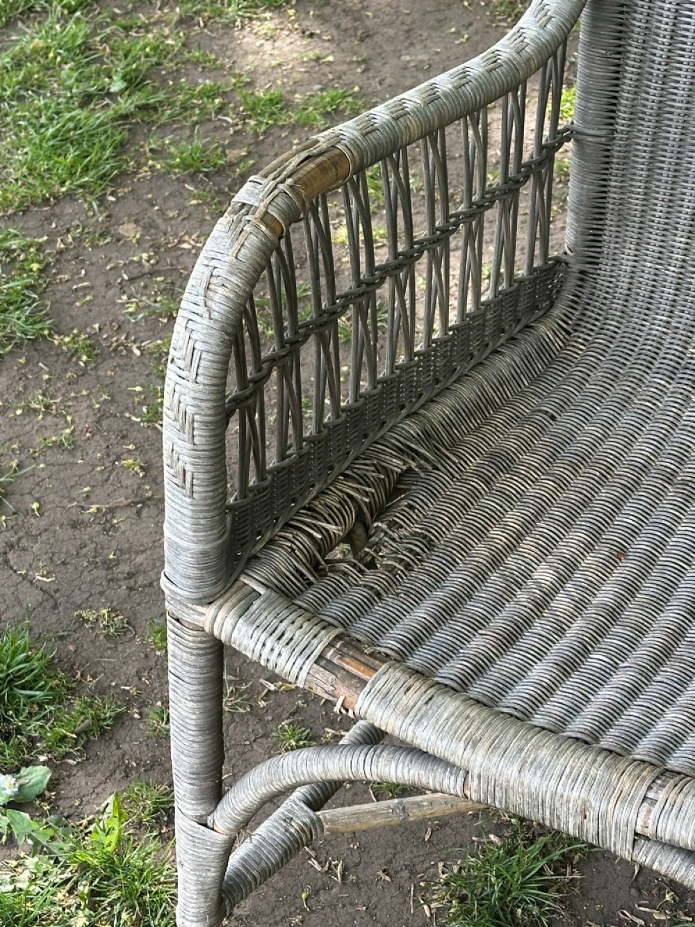 An early 20th-century handwoven cane armchair featuring a high backrest, openwork arms, and curved structural stretchers in weathered grey. View III