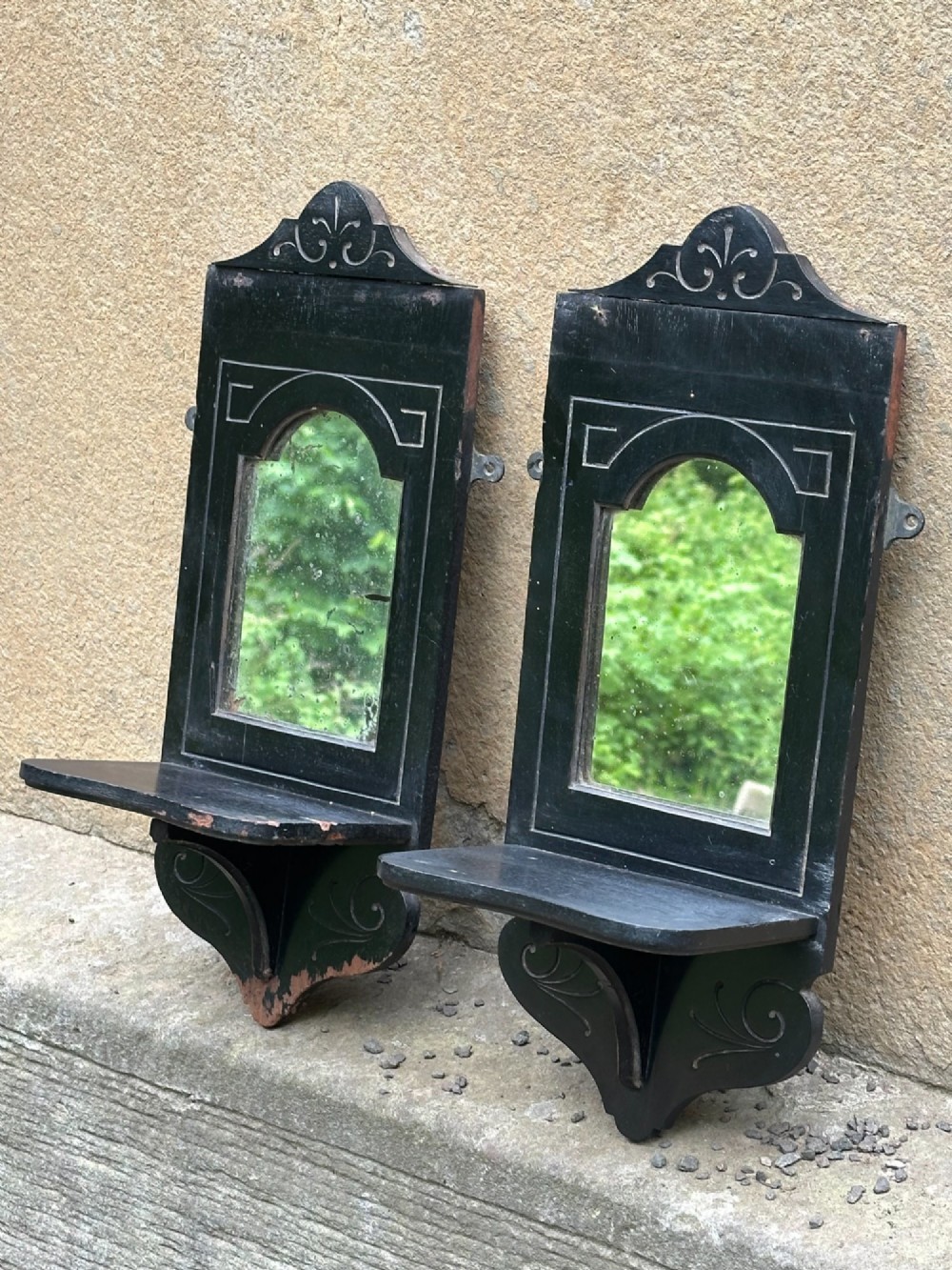 A pair of late 19th-century black ebonised wooden wall girandoles with arched mirror plates, incised scroll detailing, and integrated shelves. View VIII