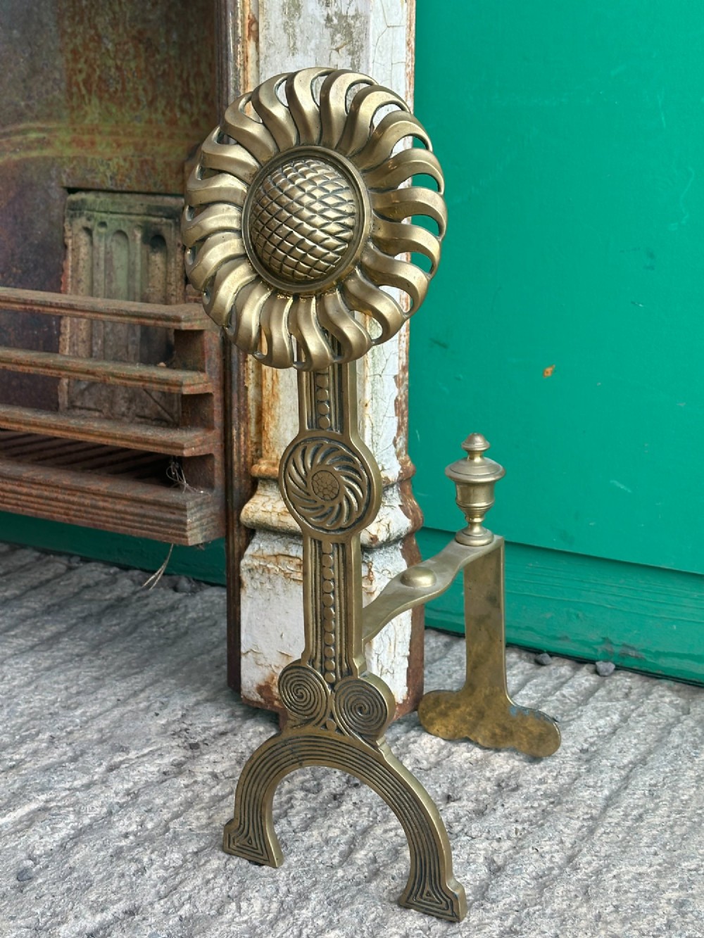 A pair of late Victorian cast brass andirons featuring stylised sunflower tops and geometric scroll detailing. View II