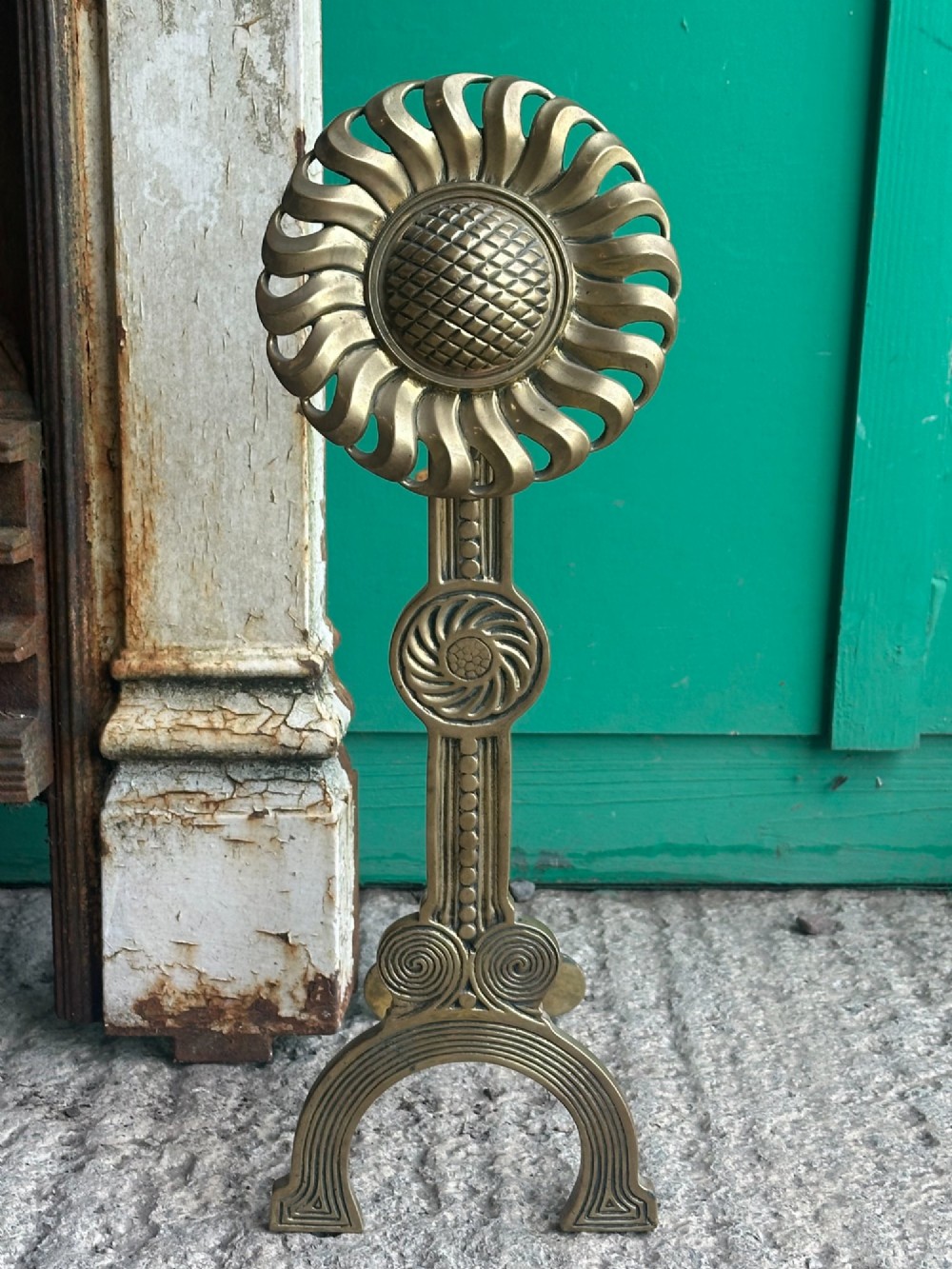 A pair of late Victorian cast brass andirons featuring stylised sunflower tops and geometric scroll detailing. View V