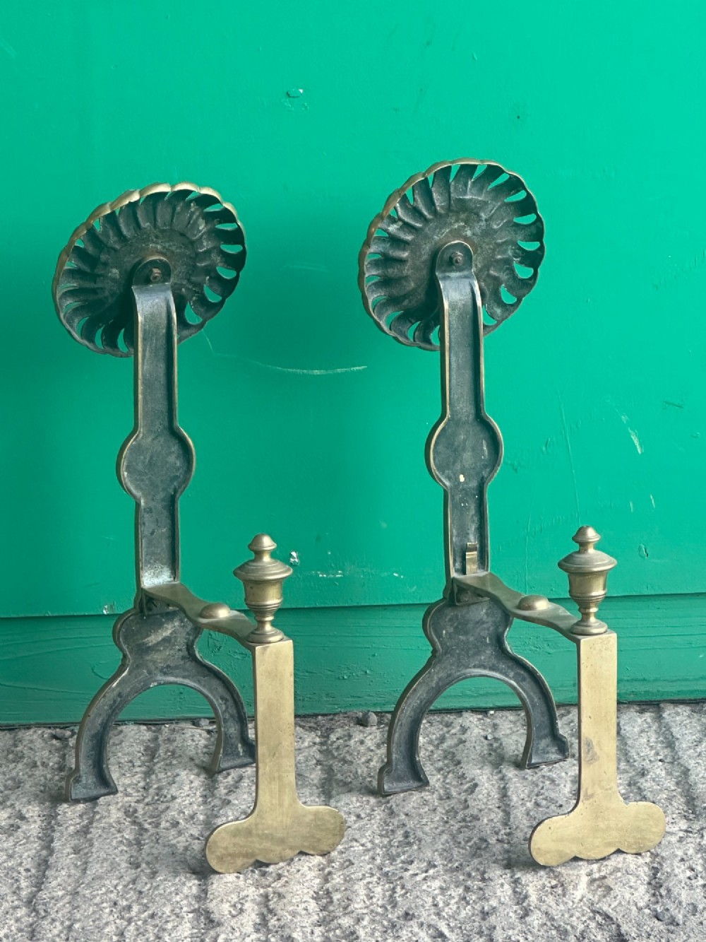 A pair of late Victorian cast brass andirons featuring stylised sunflower tops and geometric scroll detailing. View VI