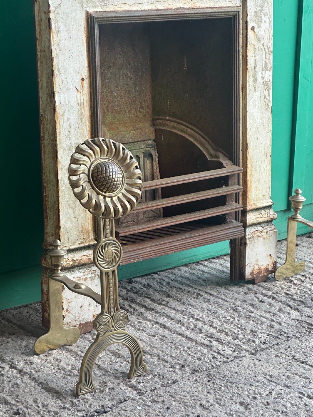 A pair of late Victorian cast brass andirons featuring stylised sunflower tops and geometric scroll detailing. View IX