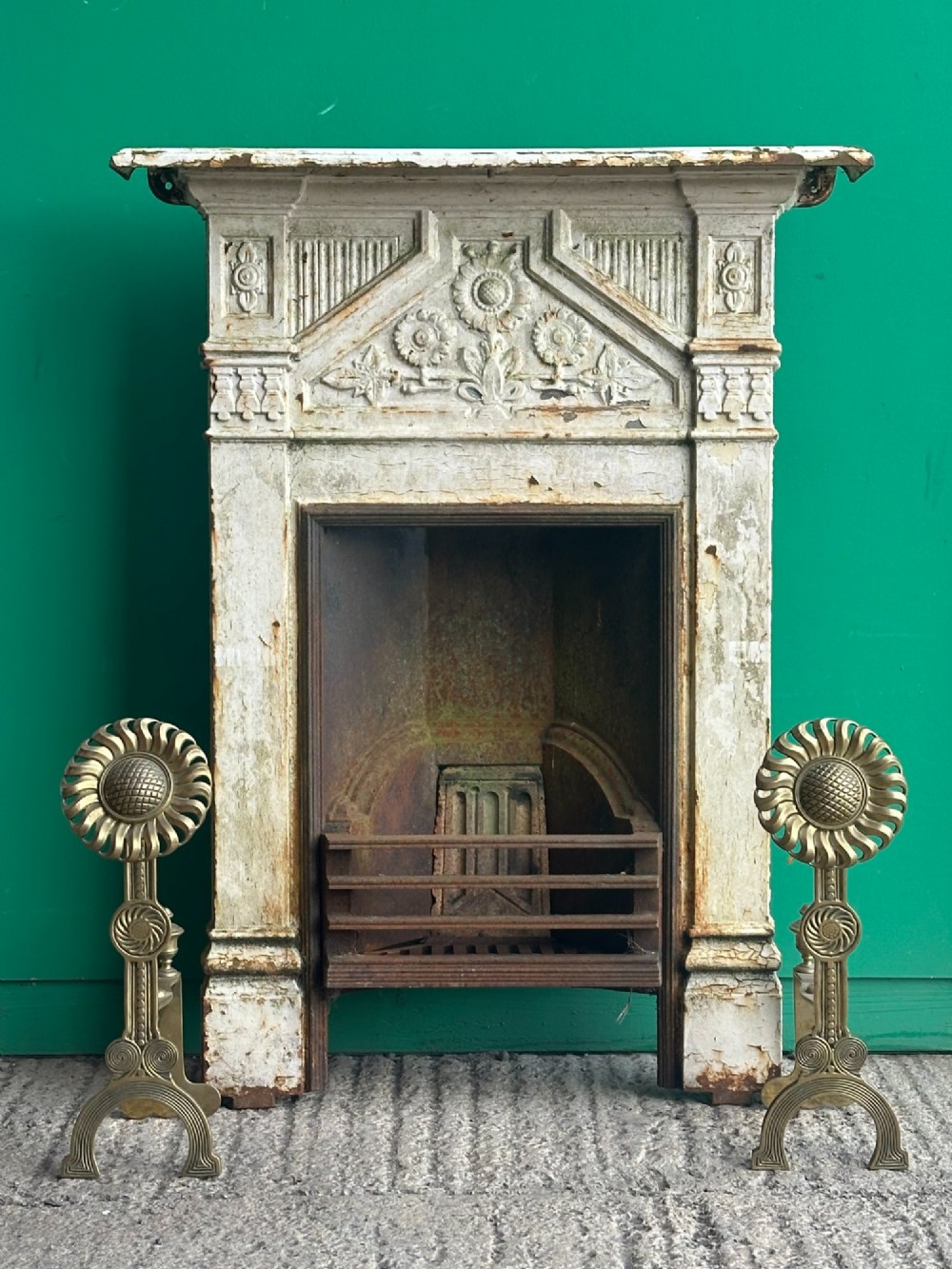 A pair of late Victorian cast brass andirons featuring stylised sunflower tops and geometric scroll detailing. View X