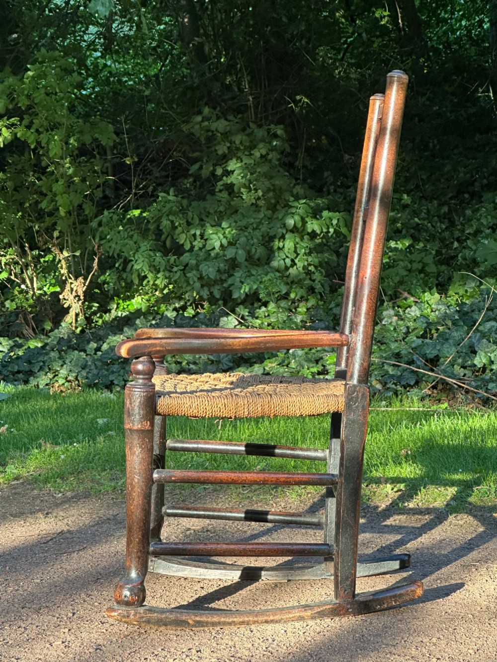 A George III dark wood rocking chair featuring a double spindle back, turned legs, and a hand-woven rush seat. View II