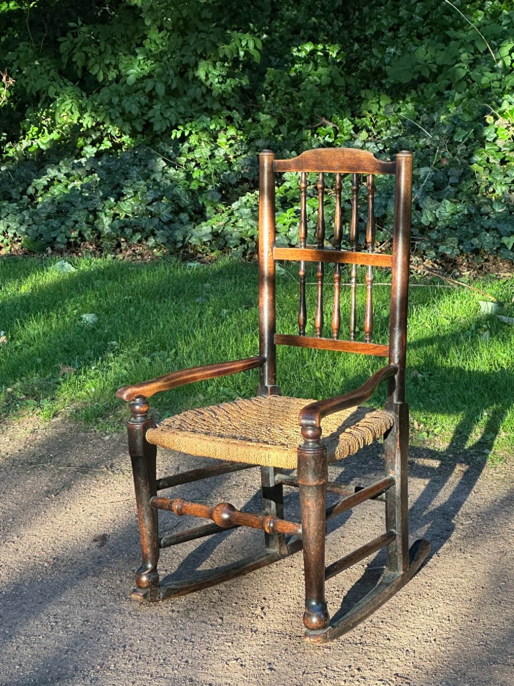 A George III dark wood rocking chair featuring a double spindle back, turned legs, and a hand-woven rush seat. View III