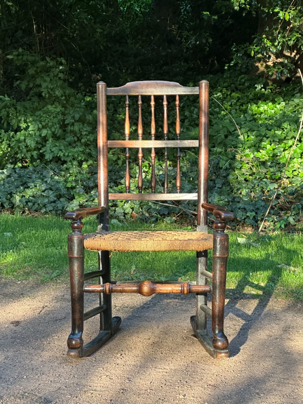 A George III dark wood rocking chair featuring a double spindle back, turned legs, and a hand-woven rush seat. View IV