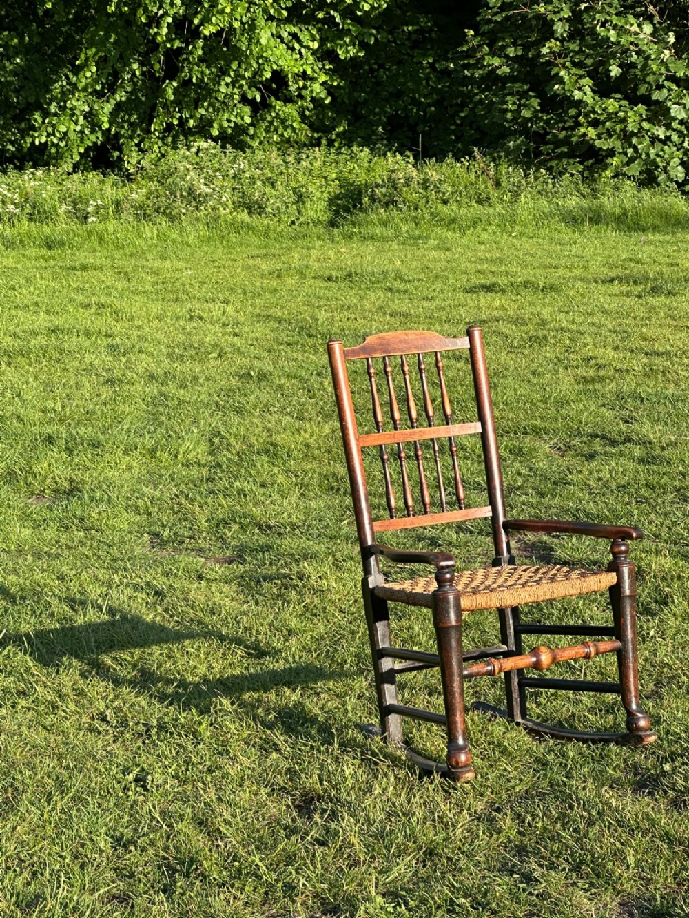A George III dark wood rocking chair featuring a double spindle back, turned legs, and a hand-woven rush seat. View VIII