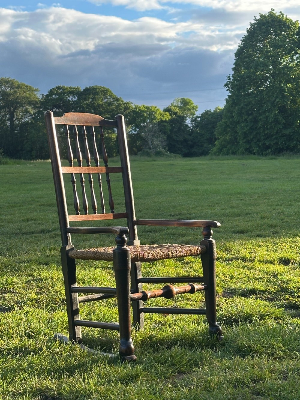 A George III dark wood rocking chair featuring a double spindle back, turned legs, and a hand-woven rush seat.