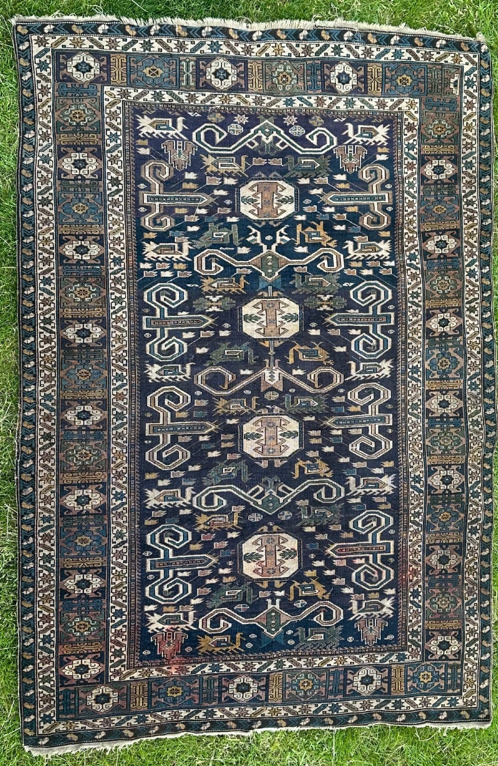 An antique East Caucasian Shirvan rug featuring a dark navy blue field filled with geometric medallions, stylized bird motifs, and multi-band patterned borders.