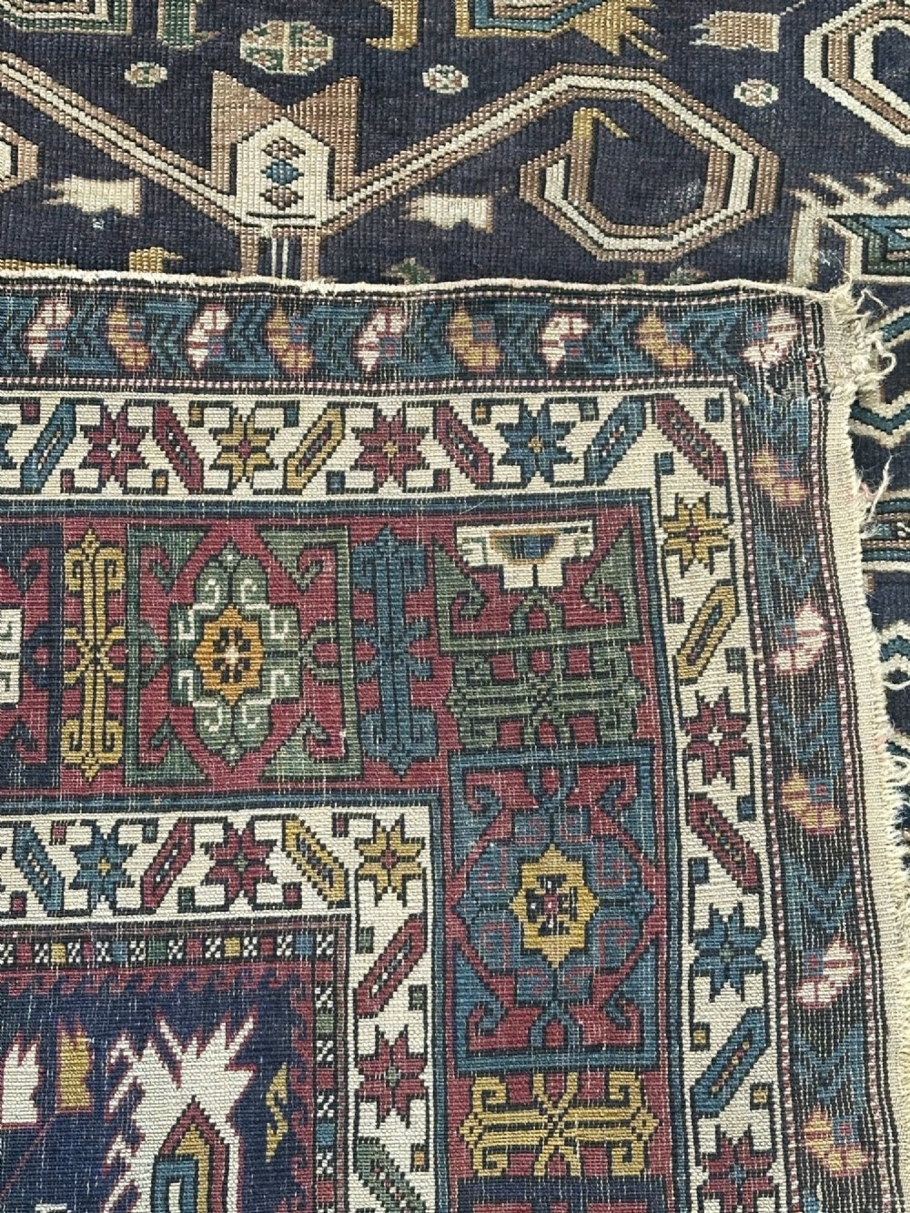 An antique East Caucasian Shirvan rug featuring a dark navy blue field filled with geometric medallions, stylized bird motifs, and multi-band patterned borders. View III