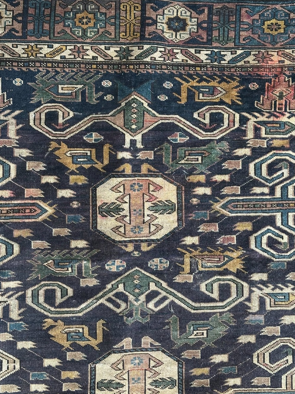 An antique East Caucasian Shirvan rug featuring a dark navy blue field filled with geometric medallions, stylized bird motifs, and multi-band patterned borders. View IV