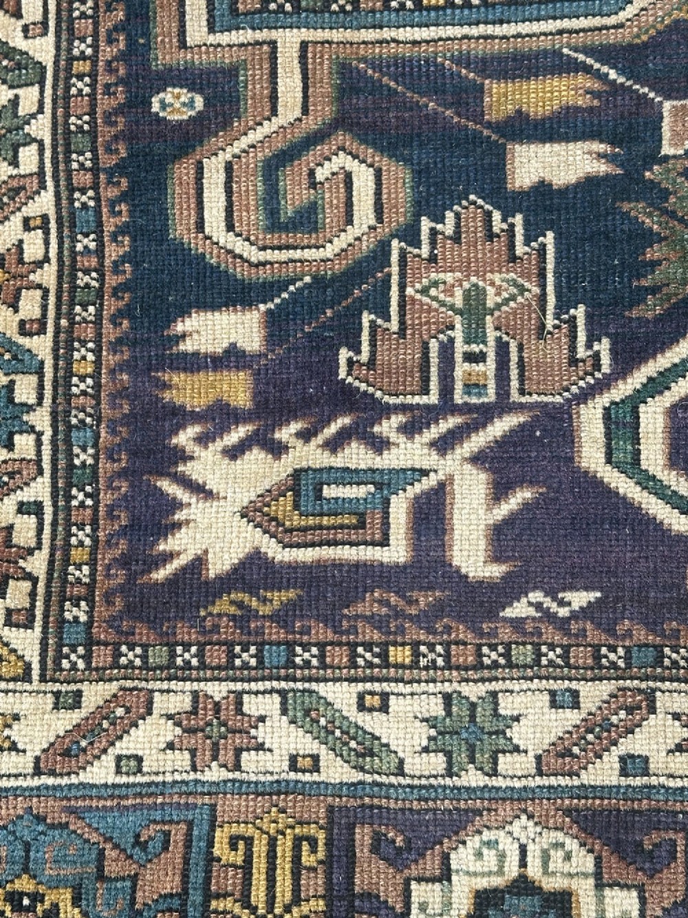 An antique East Caucasian Shirvan rug featuring a dark navy blue field filled with geometric medallions, stylized bird motifs, and multi-band patterned borders. View V