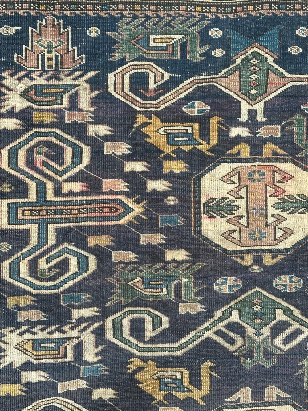 An antique East Caucasian Shirvan rug featuring a dark navy blue field filled with geometric medallions, stylized bird motifs, and multi-band patterned borders. View VII