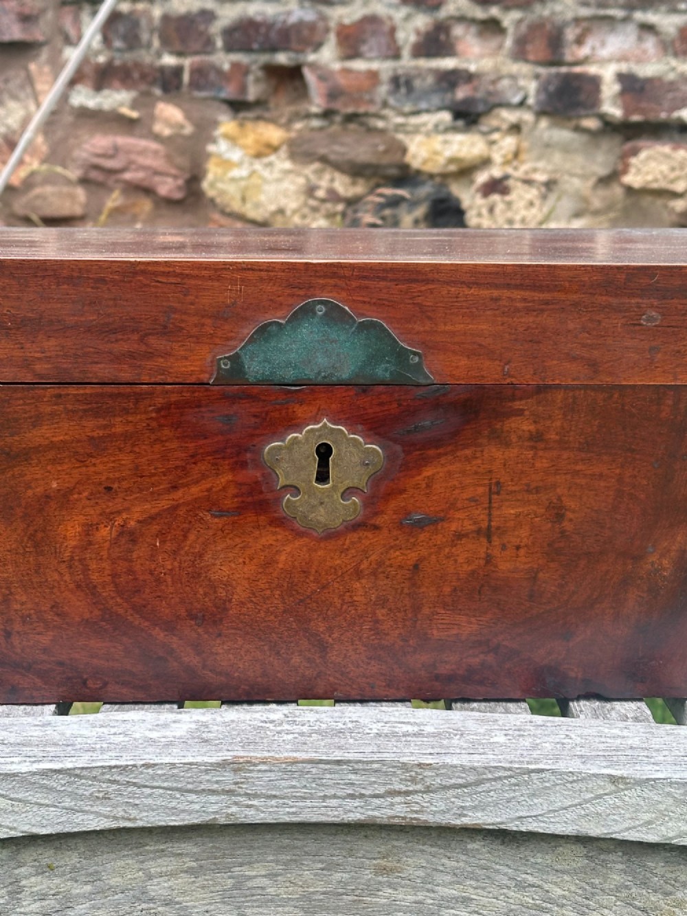 A rectangular reddish-brown padouk wood deed box featuring brass corner mounts, a central keyhole escutcheon, and brass side carrying handles. View VIII