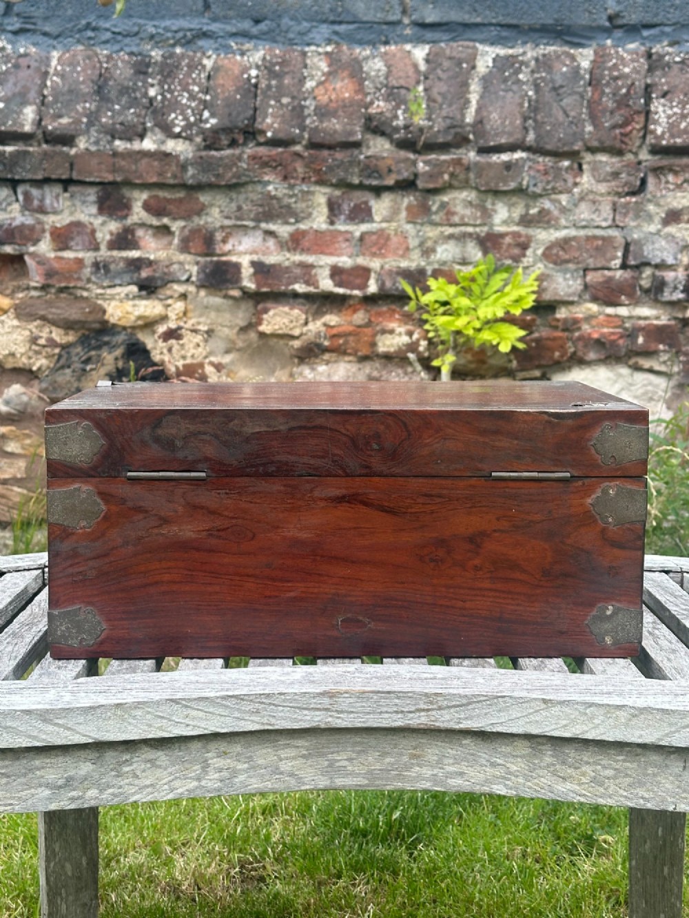 A rectangular reddish-brown padouk wood deed box featuring brass corner mounts, a central keyhole escutcheon, and brass side carrying handles. View IX