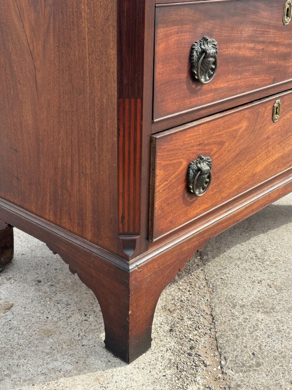 A late eighteenth-century George III mahogany chest of drawers with four graduating drawers, brass ring handles, keyhole escutcheons, and bracket feet. View X