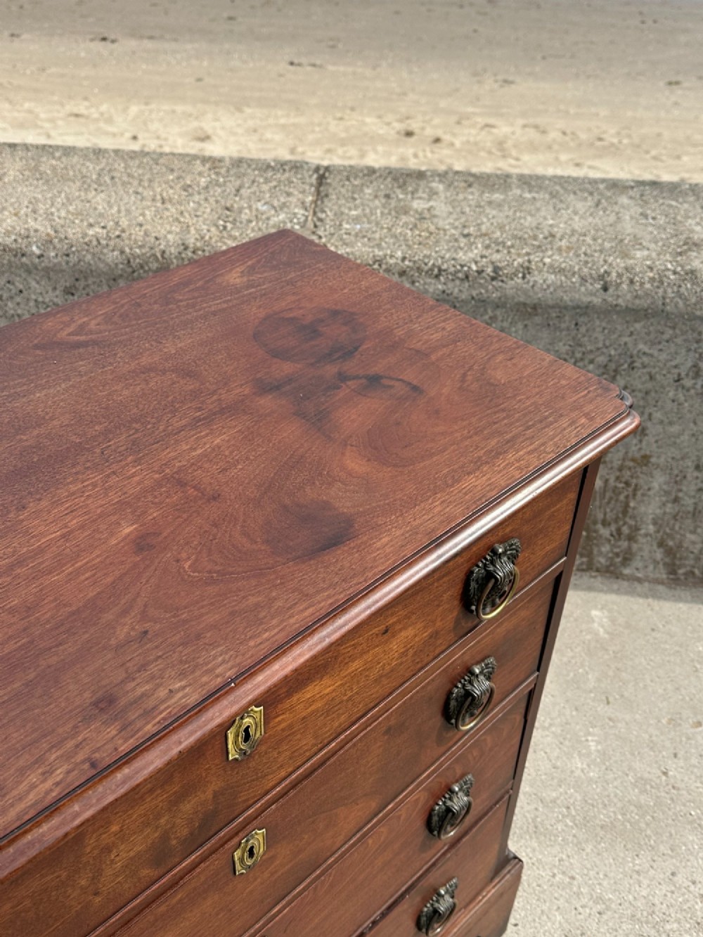 A late eighteenth-century George III mahogany chest of drawers with four graduating drawers, brass ring handles, keyhole escutcheons, and bracket feet. View XI