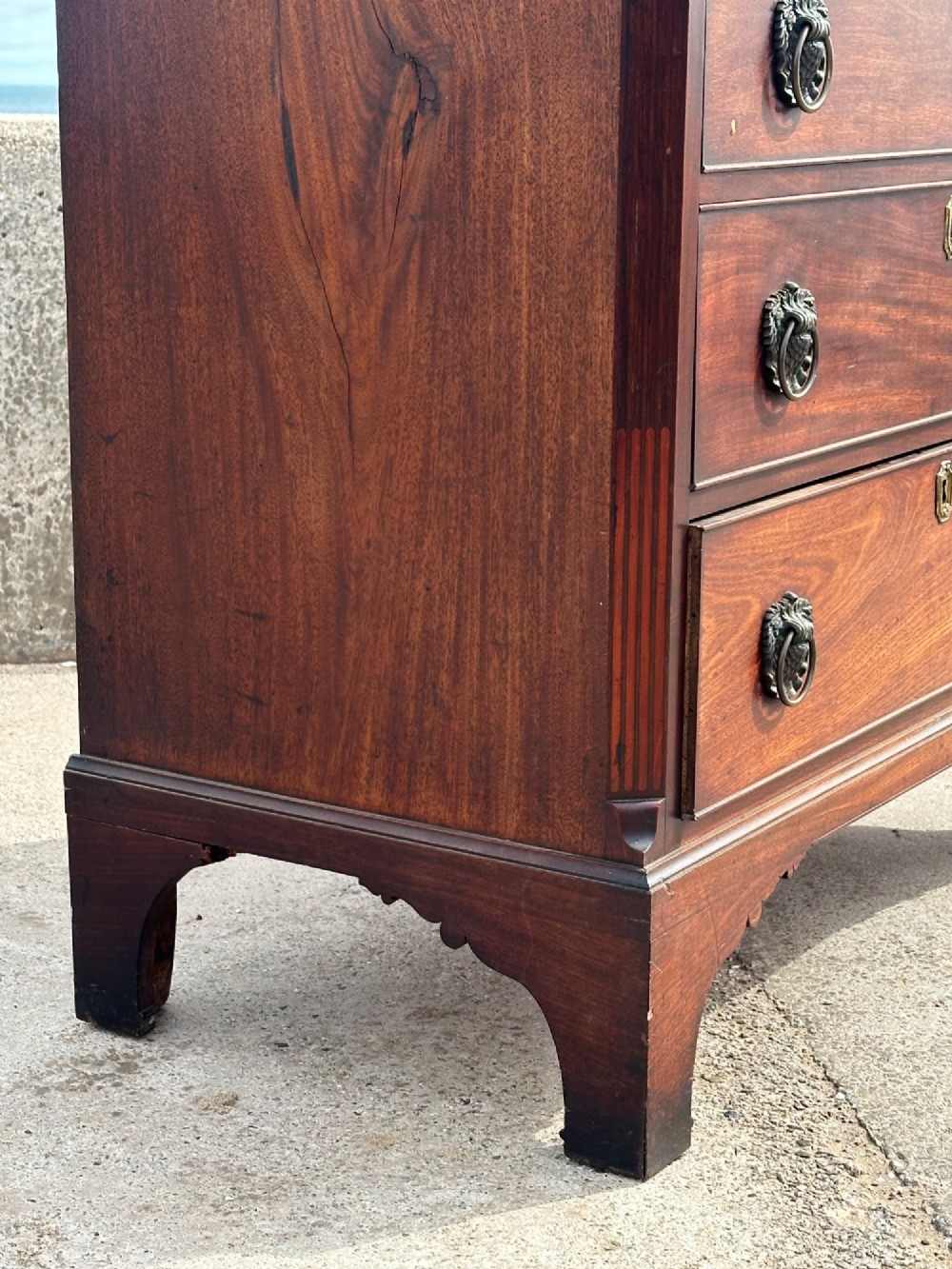 A late eighteenth-century George III mahogany chest of drawers with four graduating drawers, brass ring handles, keyhole escutcheons, and bracket feet. View XII