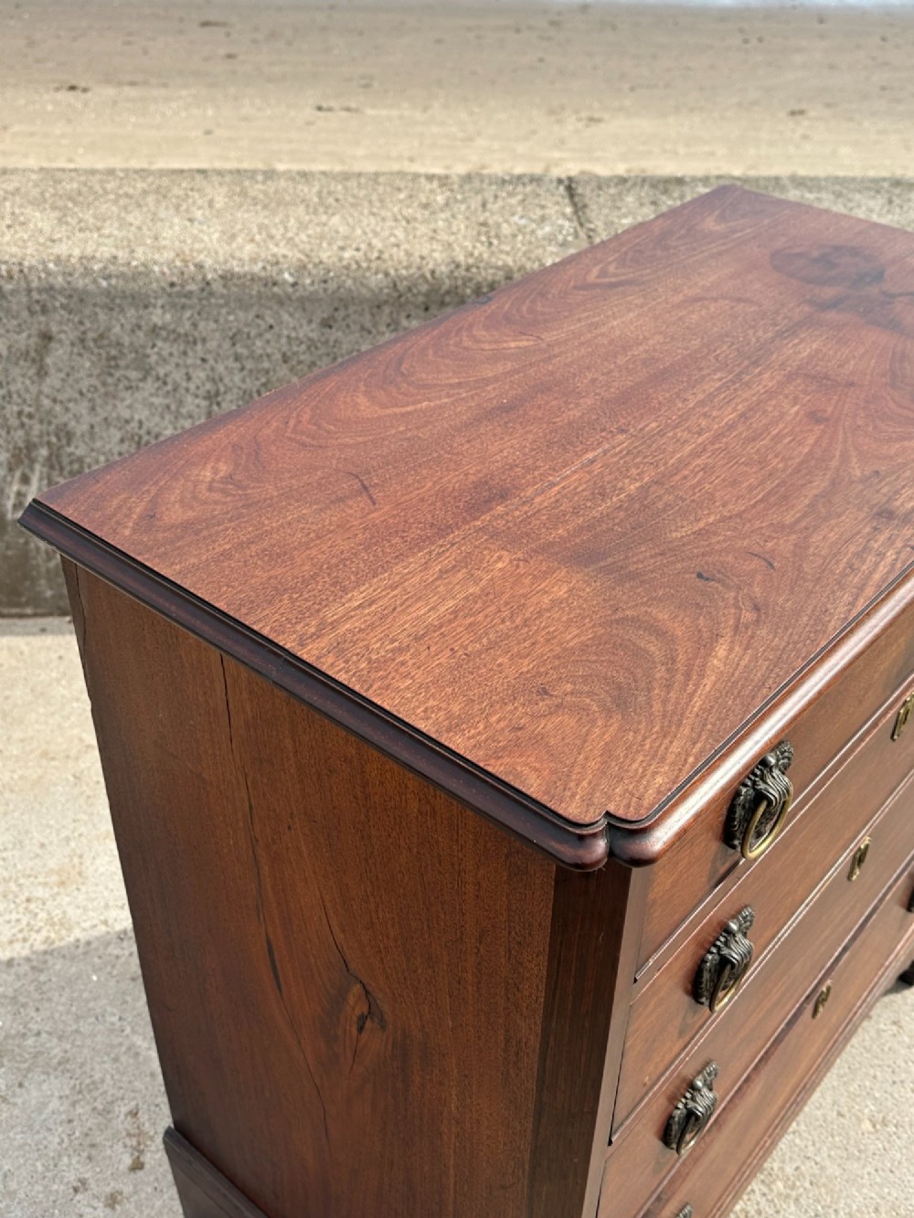 A late eighteenth-century George III mahogany chest of drawers with four graduating drawers, brass ring handles, keyhole escutcheons, and bracket feet. View XIV