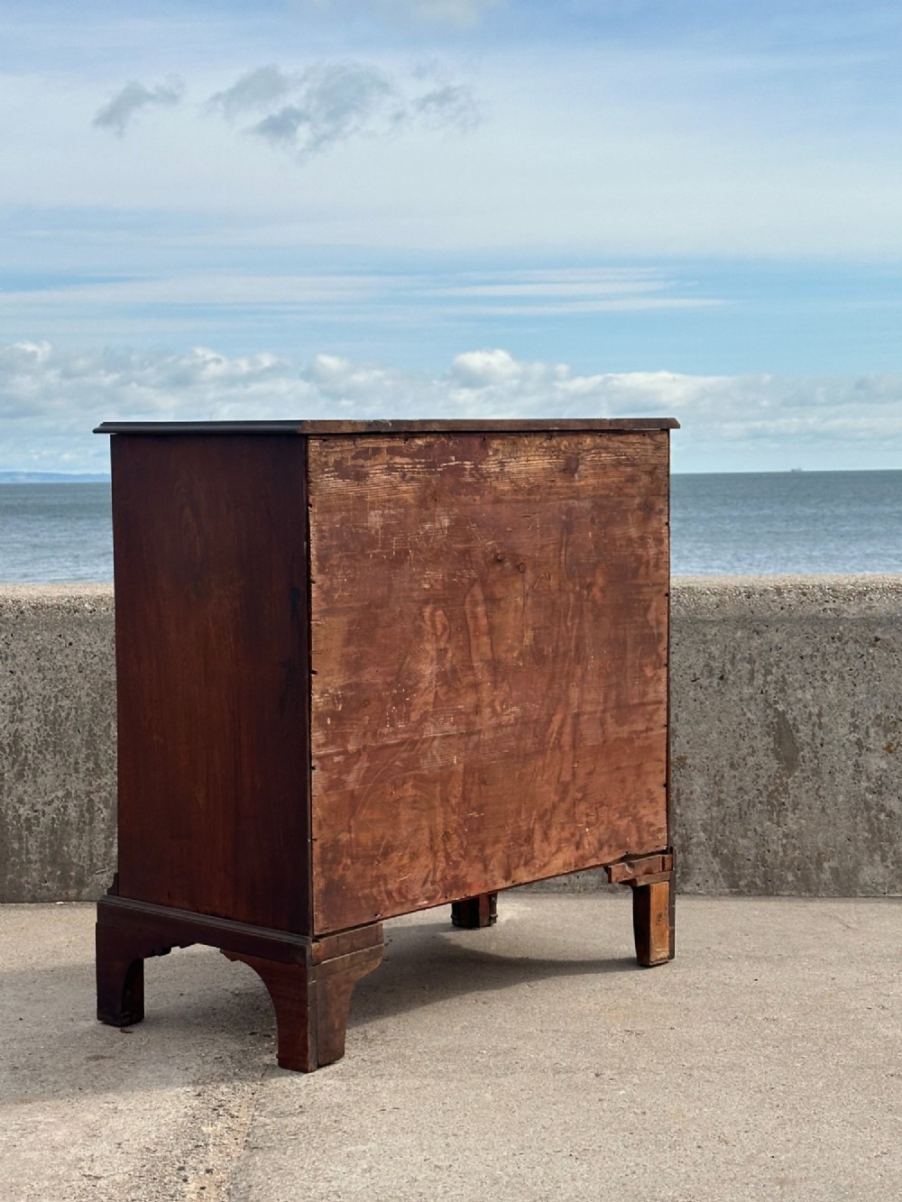 A late eighteenth-century George III mahogany chest of drawers with four graduating drawers, brass ring handles, keyhole escutcheons, and bracket feet. View XV
