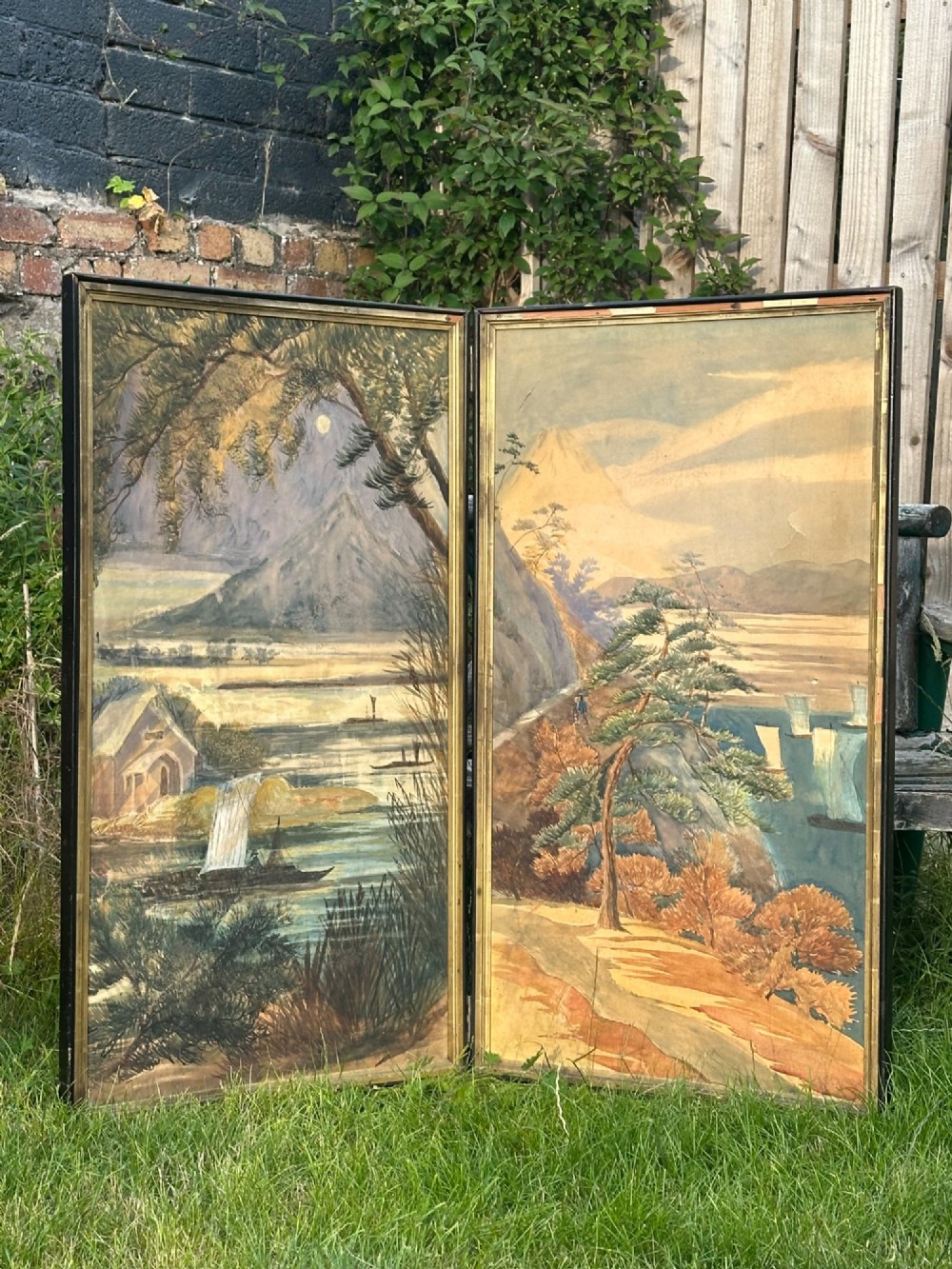 A late nineteenth-century two-panel folding screen featuring hand-painted Japanese coastal and mountainous landscapes framed in dark wood.