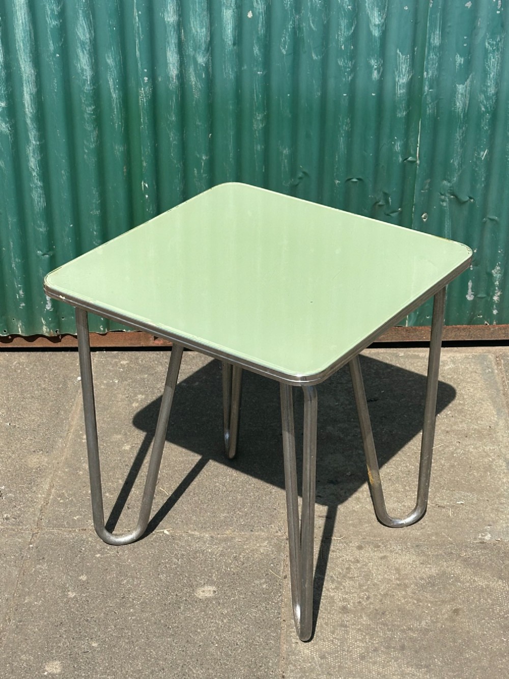 A 1930s Art Deco side table with a sage green rectangular top supported by continuous chrome tubular steel legs. View III