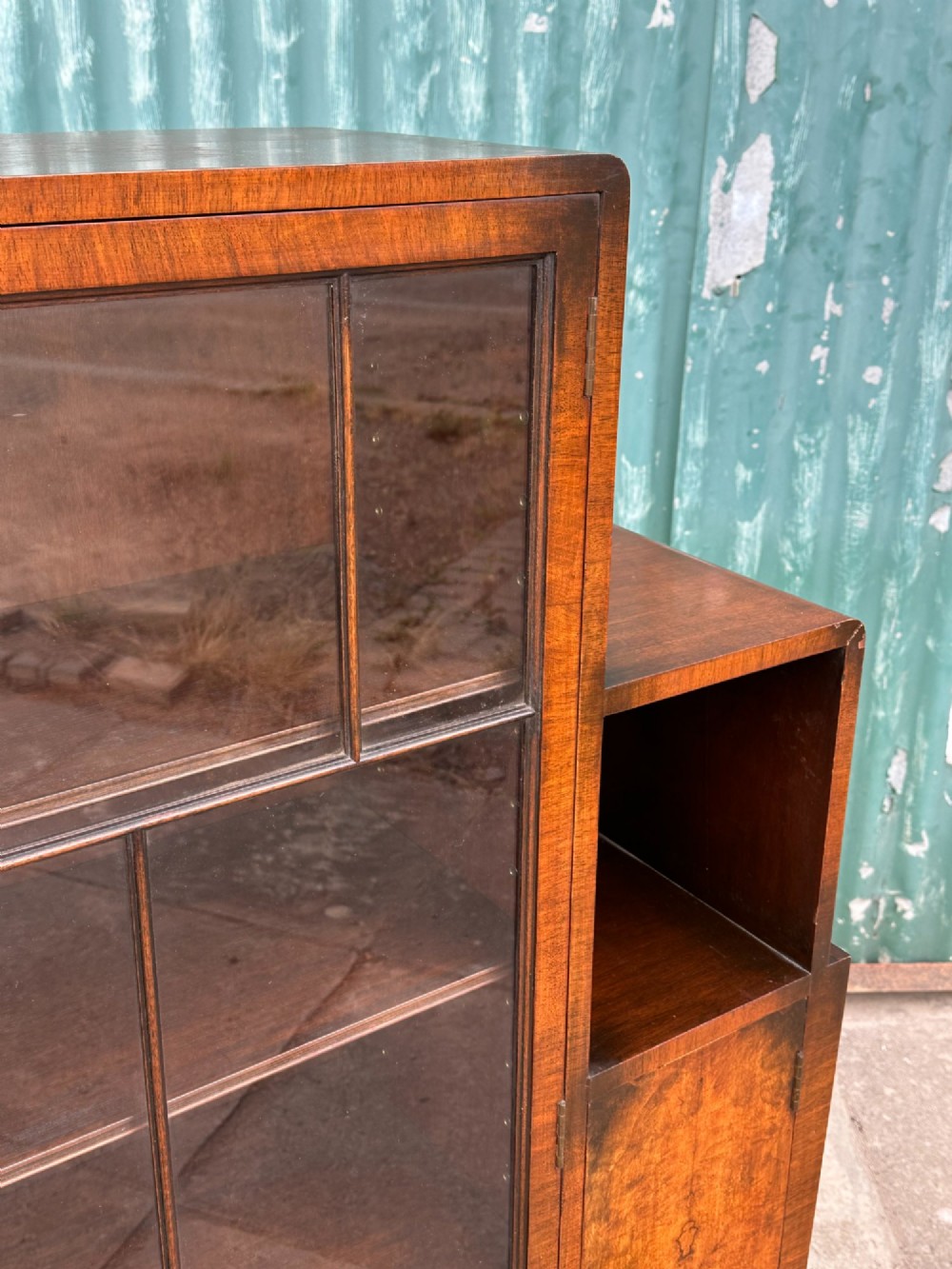 An architectural 1930s Art Deco cabinet made of warm brown walnut wood with a tall central glazed door flanked by lower cupboard doors and open alcoves. View III